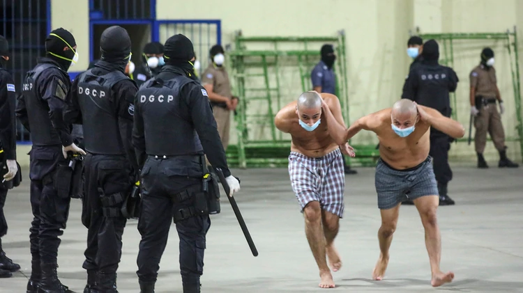 En esta foto publicada por la Oficina de Prensa de la Presidencia de El Salvador, la policía usa máscaras como precaución contra los nuevos internos. (Oficina de prensa del presidente de El Salvador a través de AP)