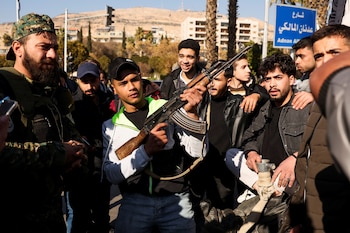 Un hombre sostiene un arma mientras la gente celebra en la Plaza de los Omeyas mientras retiran la estatua del difunto presidente de Siria, Hafez al-Assad, padre de Bashar al-Assad, después de que Bashar al-Assad de Siria fuera derrocado en el centro de Damasco, Siria, el 15 de diciembre de 2024. REUTERS/Amr Abdallah Dalsh
